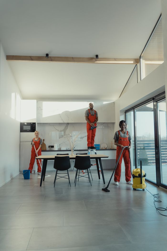 services-01 Team of professional cleaners working in a spacious, modern indoor setting.