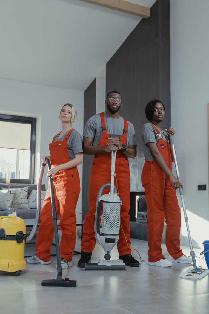 services-03 Three cleaners in uniform with equipment in a modern home interior, showcasing teamwork and professionalism.